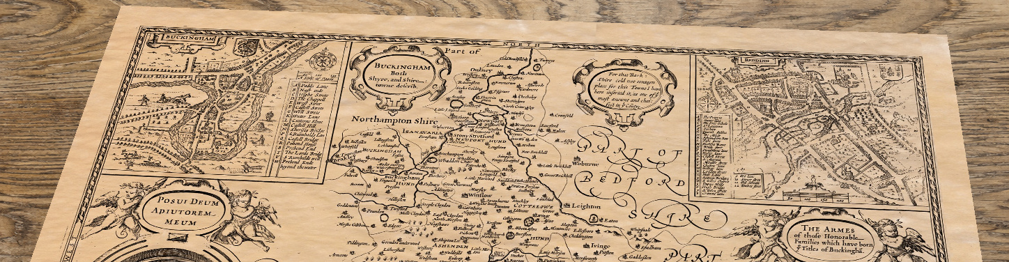 Upper section of Old Map of Buckinghamshire, 1610 by John Speed, lying at an angle on an antique ash table