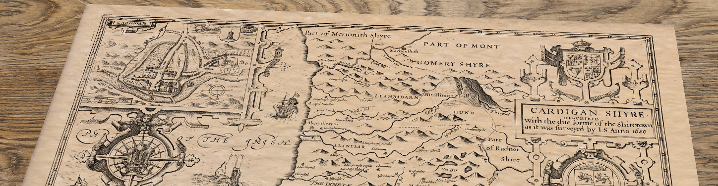 Upper section of Cardiganshire - an old map by John Speed, lying at an angle on an antique ash table