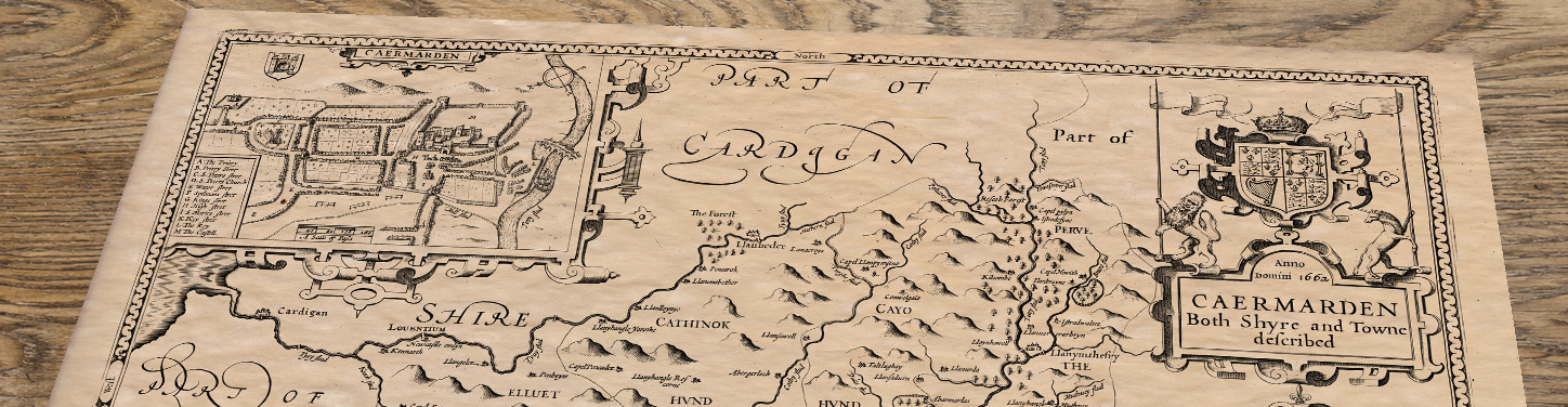 Upper section of An old map of Carmarthenshire by John Speed, lying at an angle on an antique ash table