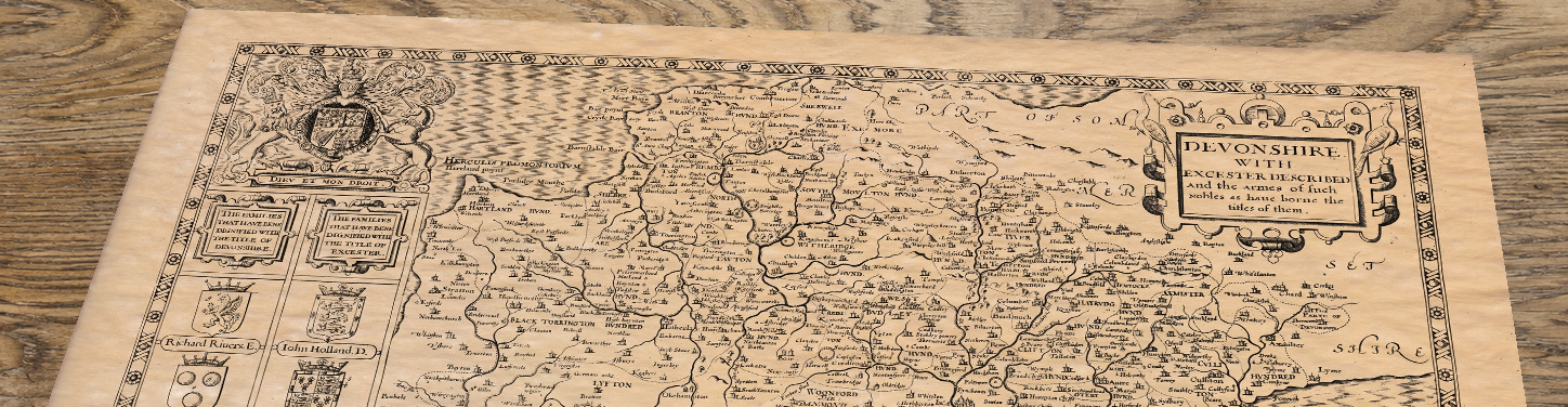 Upper section of Old Map of Devon, lying at an angle on an antique ash table