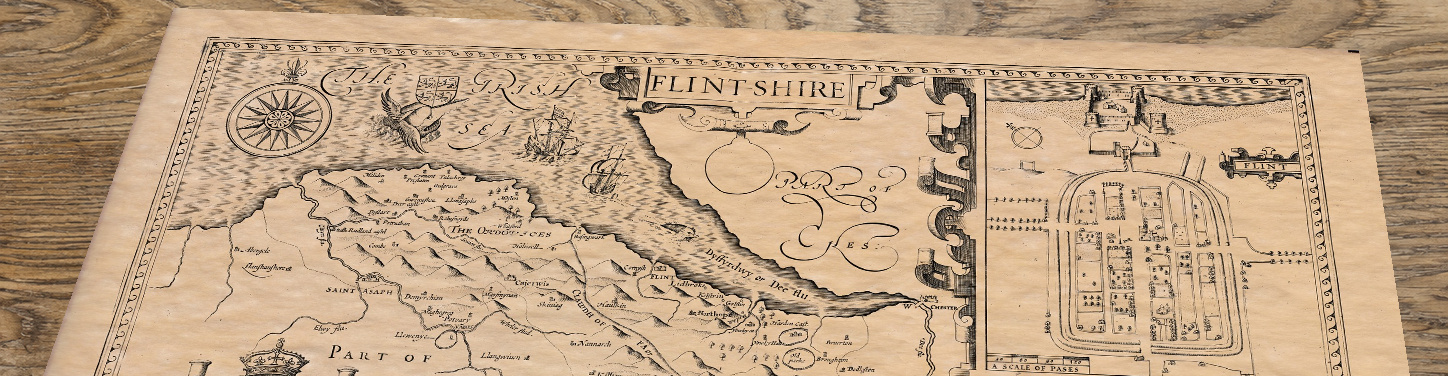 Upper section of Flintshire - an old map by John Speed, lying at an angle on an antique ash table