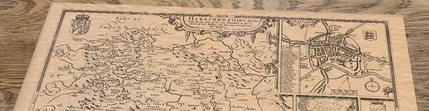 Upper section of Old Map of Herefordshire, lying at an angle on an antique ash table