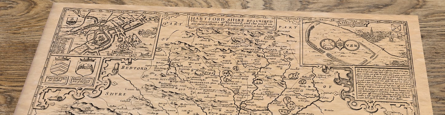 Upper section of Old Map of Hertfordshire by John Speed, 1611, lying at an angle on an antique ash table