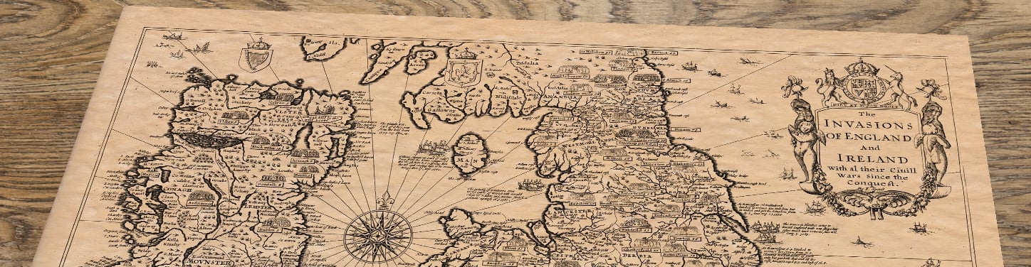 Upper section of Old Map of England & Ireland – Invasions and Civil Wars, lying at an angle on an antique ash table