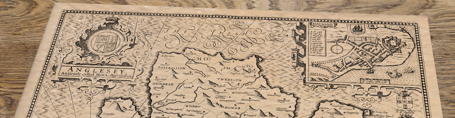 Upper section of Anglesey - an old map by John Speed, lying at an angle on an antique ash table