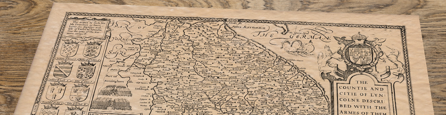 Upper section of Old Map of Lincolnshire, lying at an angle on an antique ash table