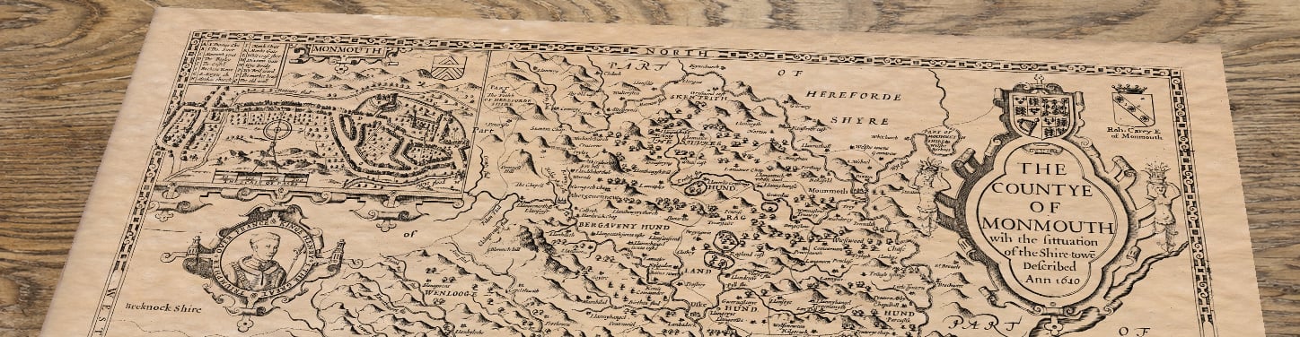 Upper section of Monmouthshire - an old map by John Speed, lying at an angle on an antique ash table