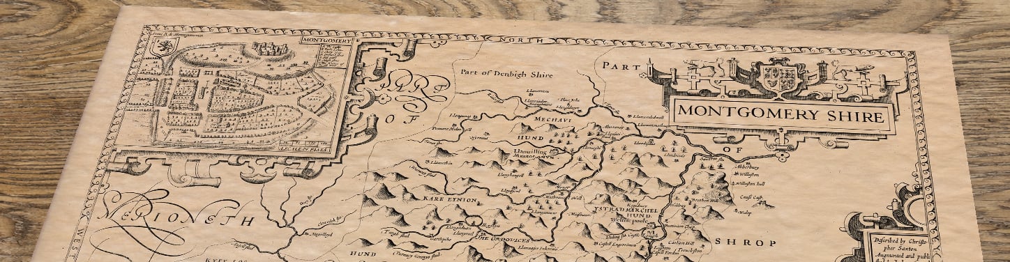 Upper section of Montgomery - an old map by John Speed, lying at an angle on an antique ash table