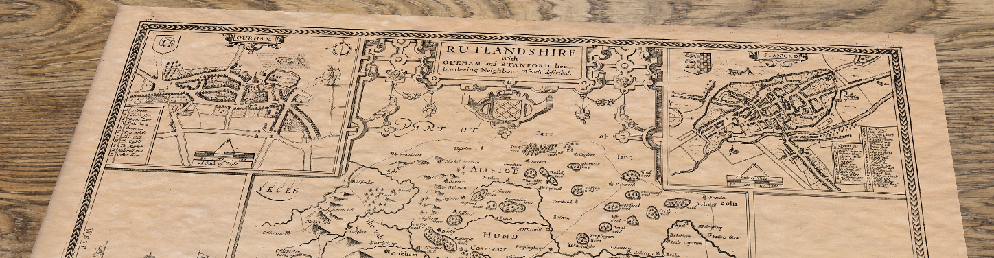 Upper section of Old Map of Rutland by John Speed, 1676, lying at an angle on an antique ash table