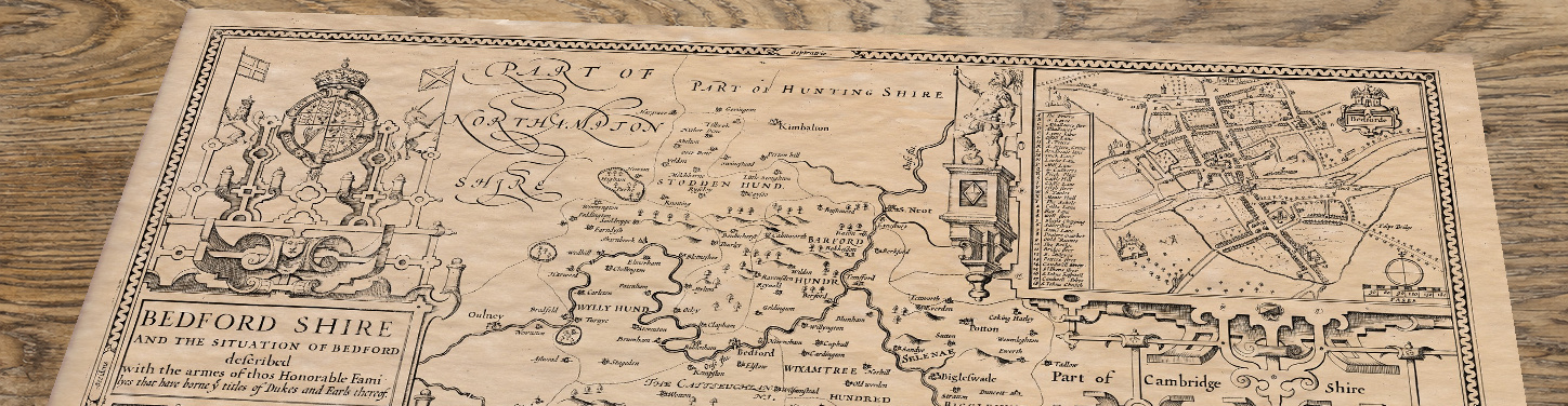 Upper section of John Speed’s Bedfordshire map lying at an angle on an antique ash table